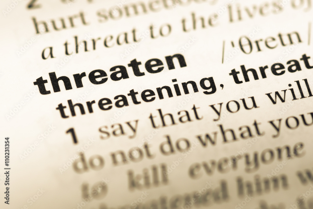 Close up of old English dictionary page with word threaten Close up of old English dictionary page with word threaten