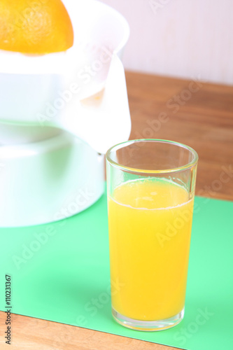 orange on squeezer, juicer and glass of orange juice on the table