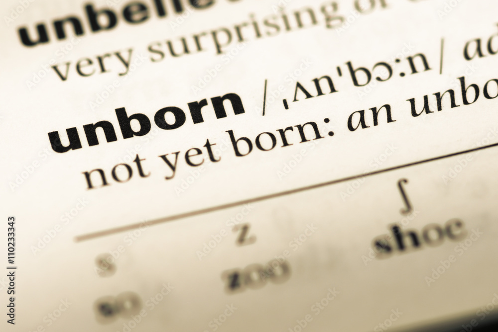 Close up of old English dictionary page with word unborn Close up of old English dictionary page with word unborn