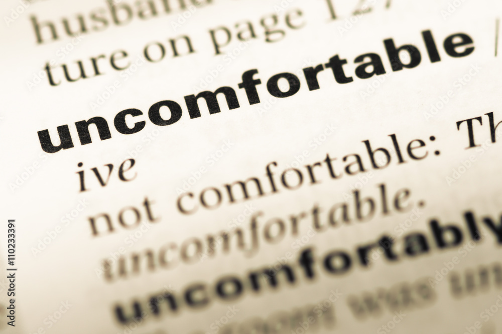 Obraz premium Close up of old English dictionary page with word uncomfortable