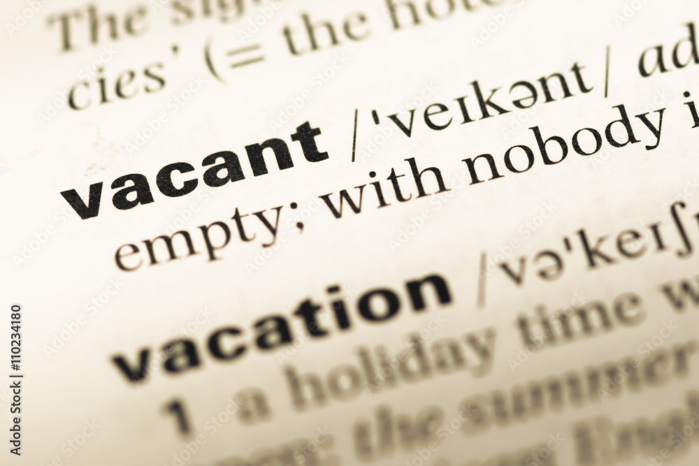 Close up of old English dictionary page with word vacant Close up of old English dictionary page with word vacant