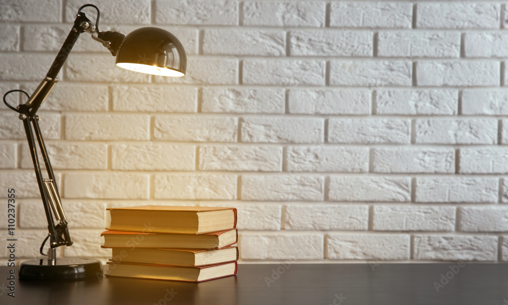 Modern lamp and books on the desk on white wall background Modern lamp and books on the desk on white wall background