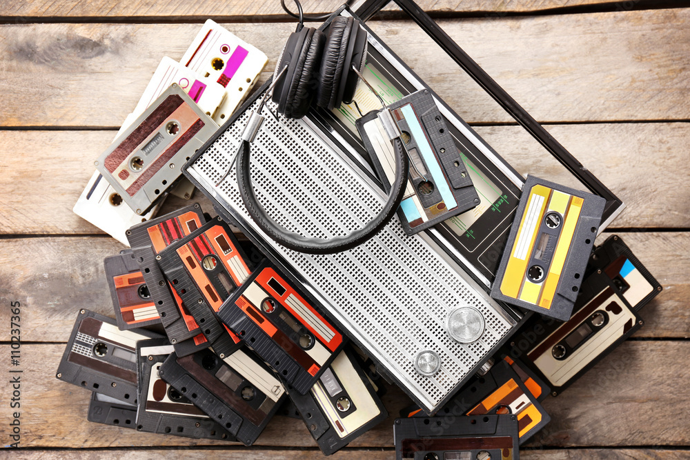 Tape recorder and retro cassettes with headphones on wooden table background Tape recorder and retro cassettes with headphones on wooden table background