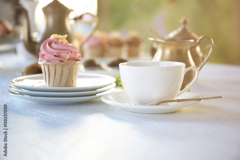 Cupcake with pink cream and cup of tea on wooden table indoors Cupcake with pink cream and cup of tea on wooden table indoors