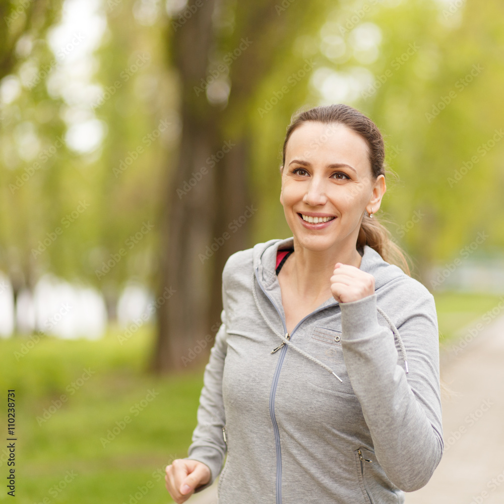Young smiling woman jogging in park in the morning Young smiling woman jogging in park in the morning