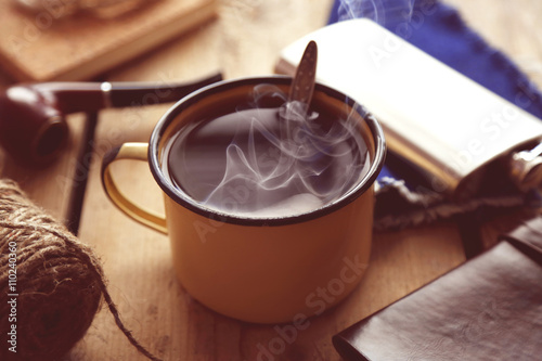 Cup of strong coffee with a flask on a wooden table, close up