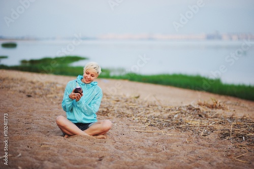 girl drinking mate she using calabash and bombilla. she sits on the beach and smiling
