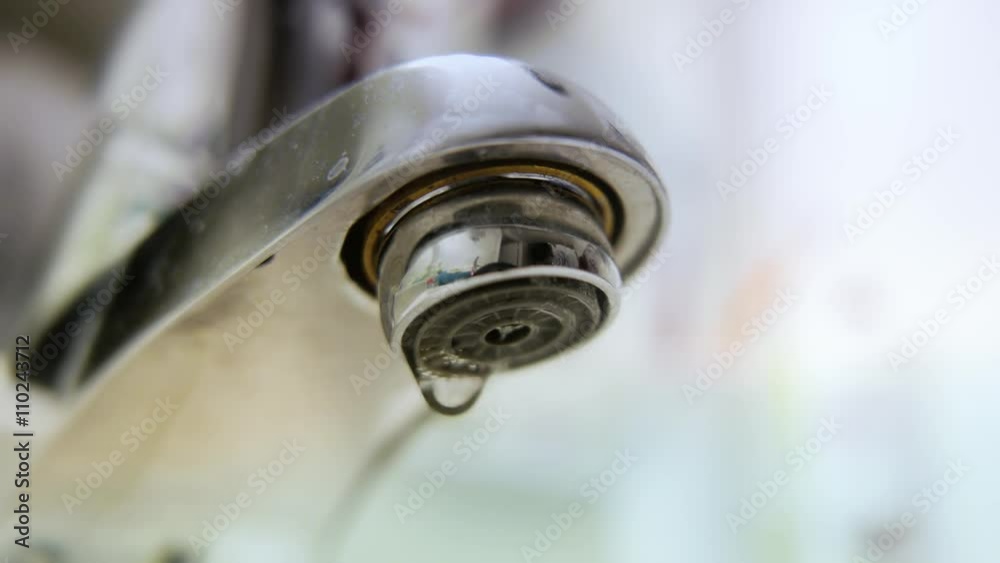 Water dripping from the tap faucet. Closeup macro shot showing the drops up close. Water dripping from the tap faucet. Closeup macro shot showing the drops up close.
