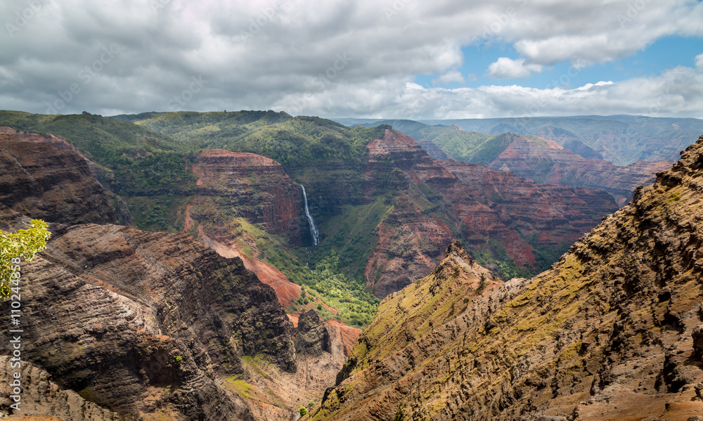 Beautiful Waipoo falls in Waimea Canyon Kauai Hawaii drops 800 feet to the valley floor. This huge colorful canyon on Hawaii's garden Isle is the result of thousands of years of water erosion .
