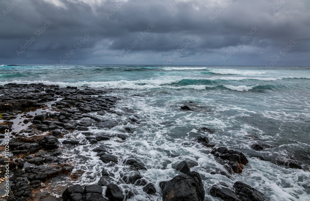 Stormy seas blow over a rocky volcanic shore in Kauai , Hawaii. Stormy seas blow over a rocky volcanic shore in Kauai , Hawaii.