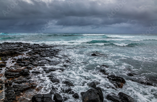 Foto Stormy seas blow over a rocky volcanic shore in Kauai , Hawaii.