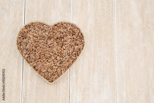 Diet healthcare healthy food. Raw flax seeds linseed heart shaped on wooden board background.