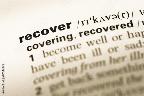 Close up of old English dictionary page with word recover