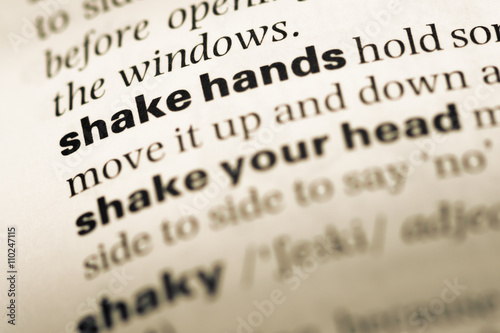 Close up of old English dictionary page with word shake hands