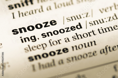 Close up of old English dictionary page with word snooze