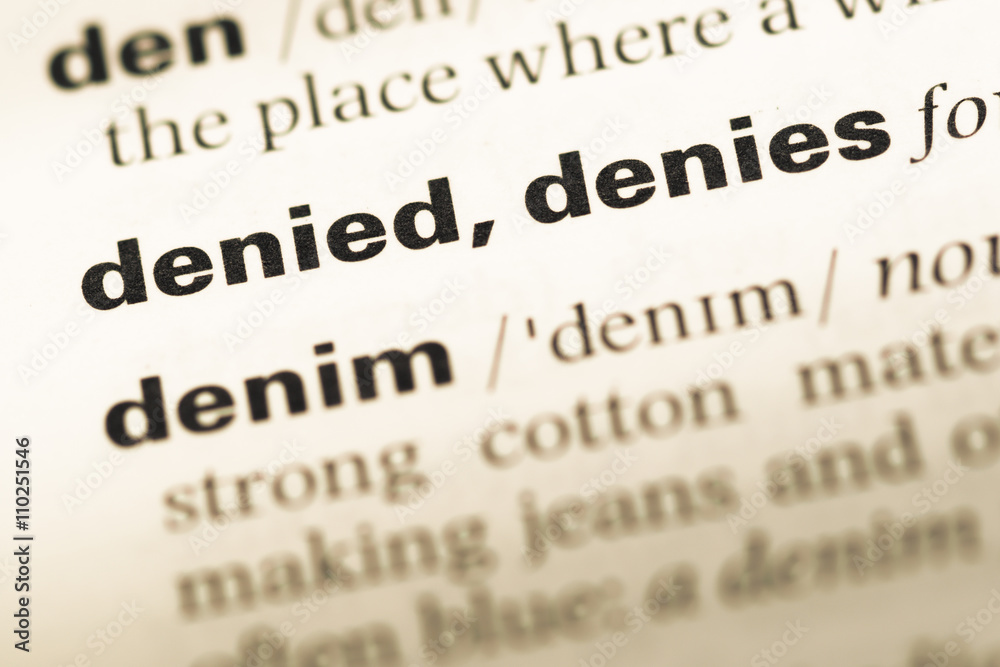 Fototapeta premium Close up of old English dictionary page with word denied denies