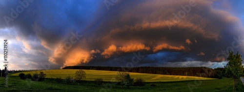 dramatically evolving the cloudy formation lit by the setting sun over the meadow and a field with blooming rape, Zabrehs highlands, North Moravia,Czech republic, panoramic view compiled from six shot © Ivan Rusek