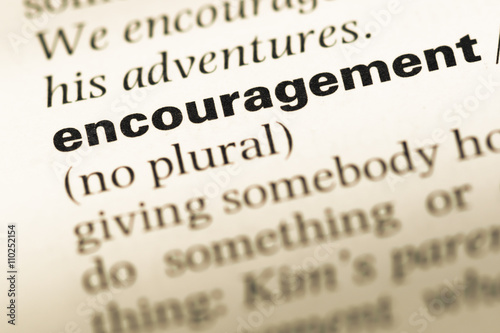 Close up of old English dictionary page with word encouragement photo