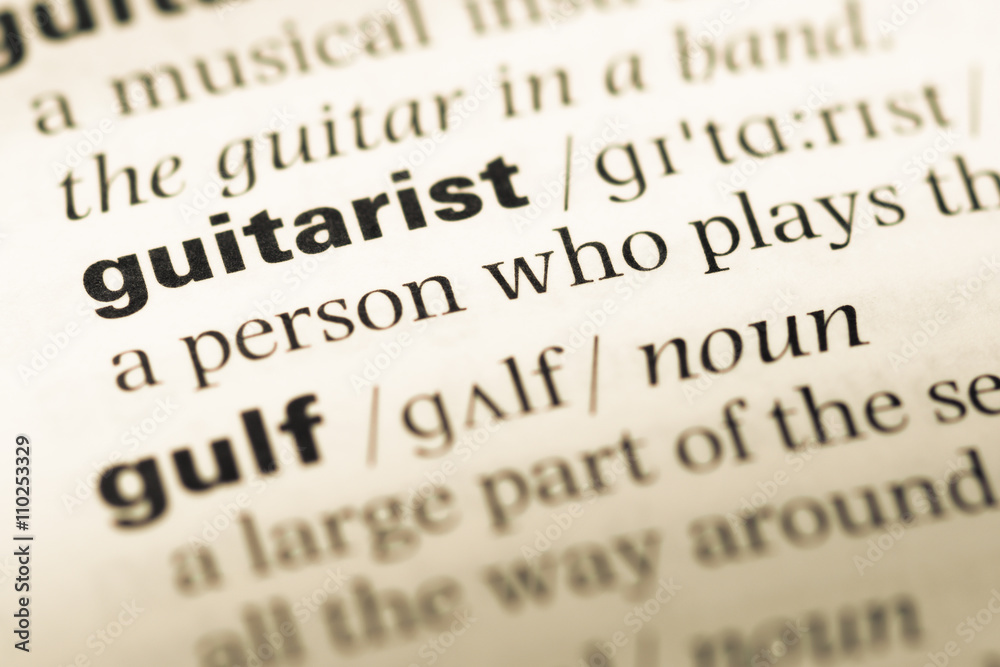 Close up of old English dictionary page with word guitarist Close up of old English dictionary page with word guitarist