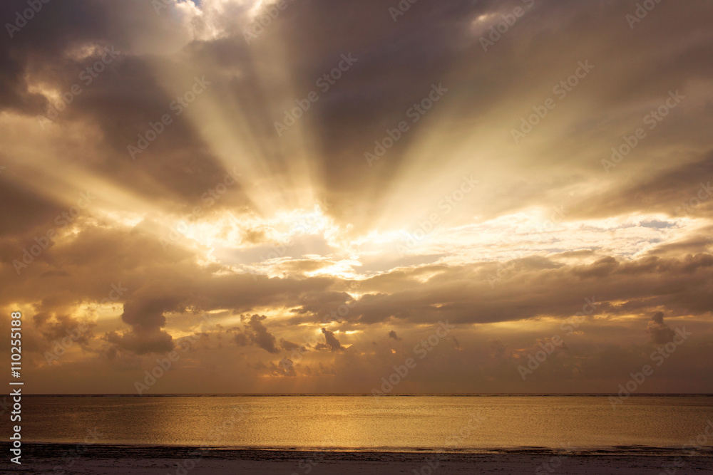 Obraz premium Beautiful sunrise over a ocean and beach with colorful clouds an