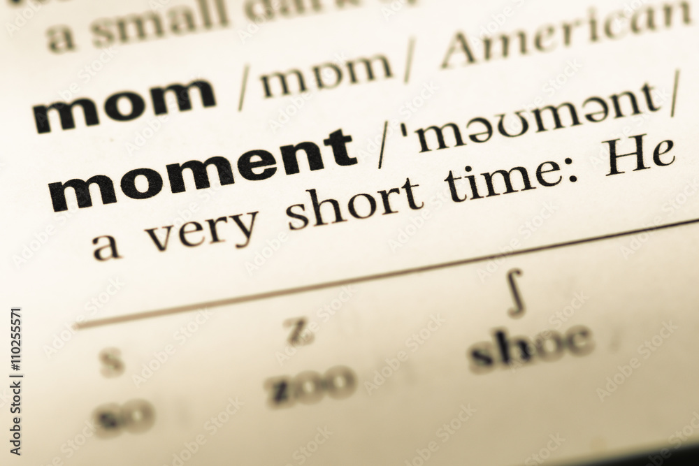 Close up of old English dictionary page with word moment Close up of old English dictionary page with word moment