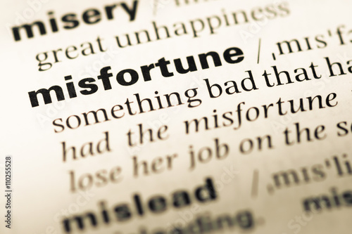 Close up of old English dictionary page with word misfortune