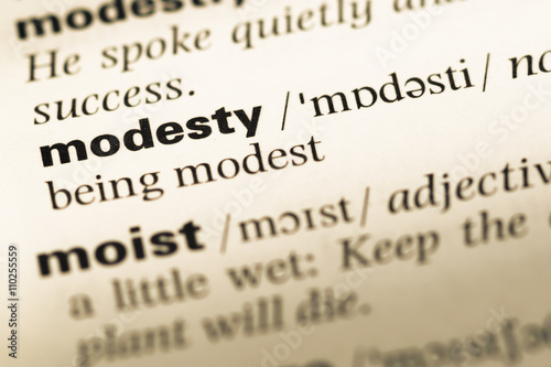 Close up of old English dictionary page with word modesty