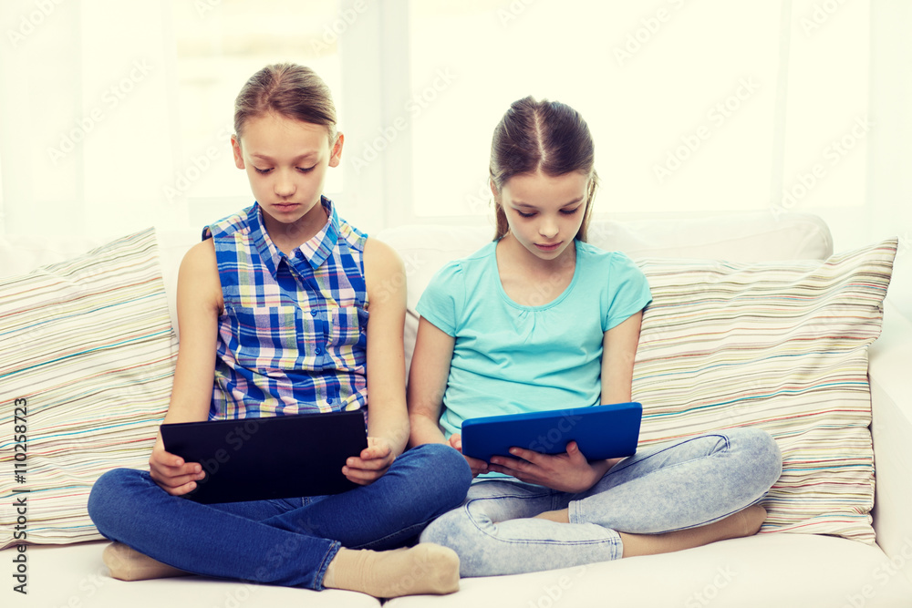 girls with tablet pc sitting on sofa at home girls with tablet pc sitting on sofa at home