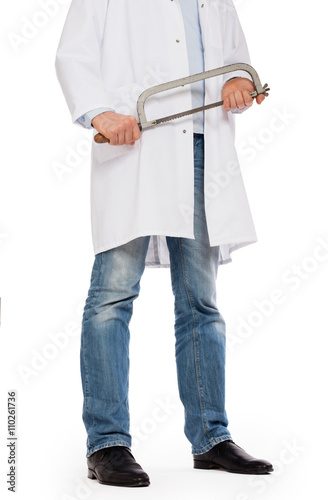Crazy doctor is holding a big saw in his hands