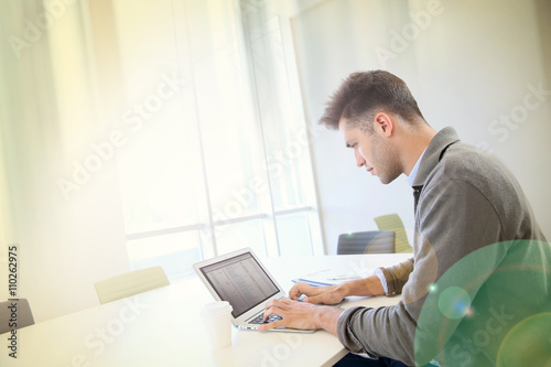 Businessman using laptop in contemporary working room