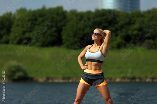 Sexy blonde fitness girl enjoying the sun at a river bank