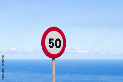 Fifty traffic sign. 50 miles per hour speed limit sign round red against blue sky