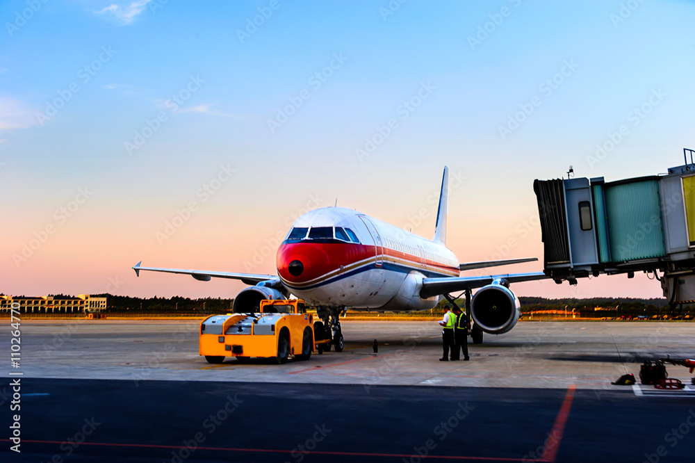 Fototapeta premium Airplane near the terminal in an airport at the sunset