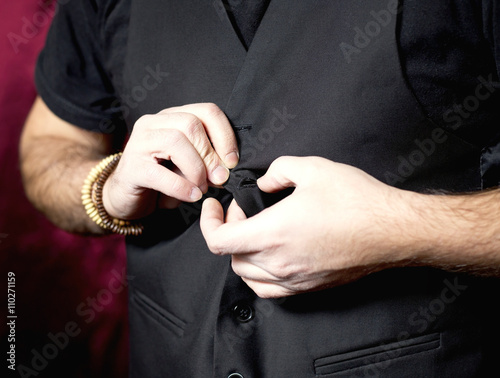 Young man adjusting his vest button.