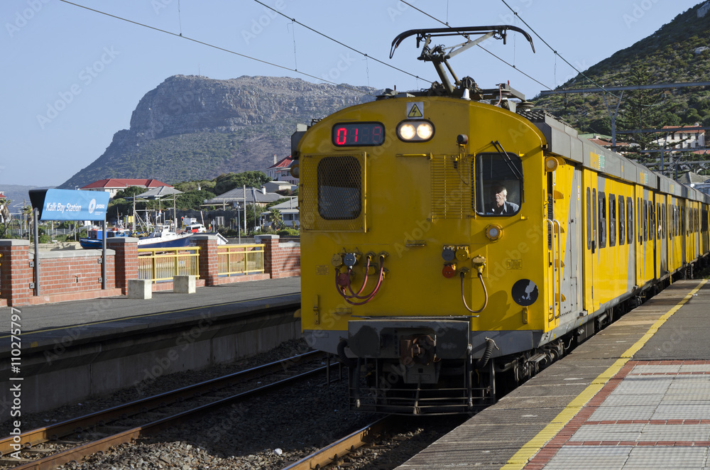 Obraz premium KALK BAY STATION WESTERN CAPE SOUTH AFRICA - APRIL 2016 - A suburban train on the coastal line to Cape Town seen here passing through the seaside resort of Kalk Bay in Southern Africa