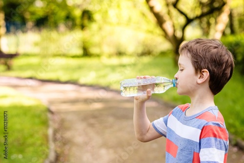 boy drinking mineral water from the plastic bottle