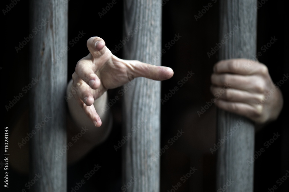 prisoner behind wooden bars begging for help - obrazy, fototapety, plakaty 
