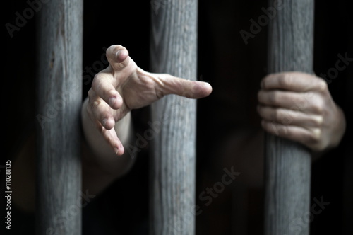 Foto prisoner behind wooden bars begging for help
