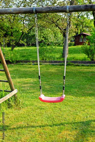 Garden red plastic children's swing in the garden