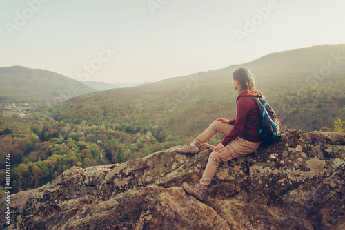 Traveler sitting on peak of rock