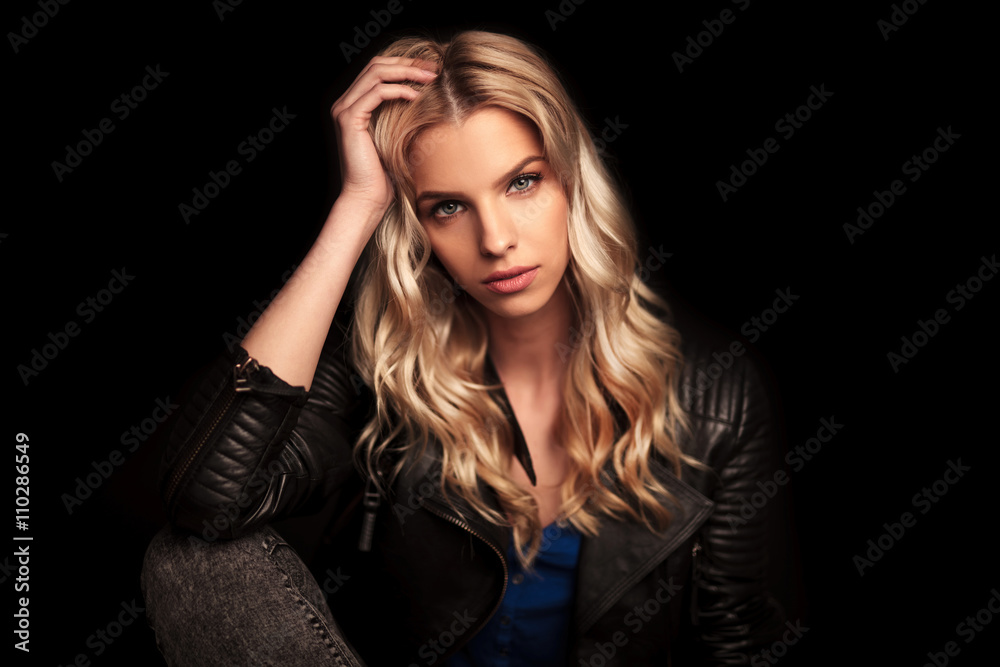 young woman in leather jacket resting her head on  palm