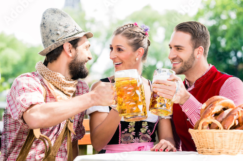 Leute mit Bier und Bretzel in Biergarten essen und trinken