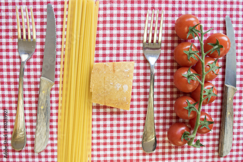 flat lay of spaghetti cherry tomatoes and parmesan between cutle photo