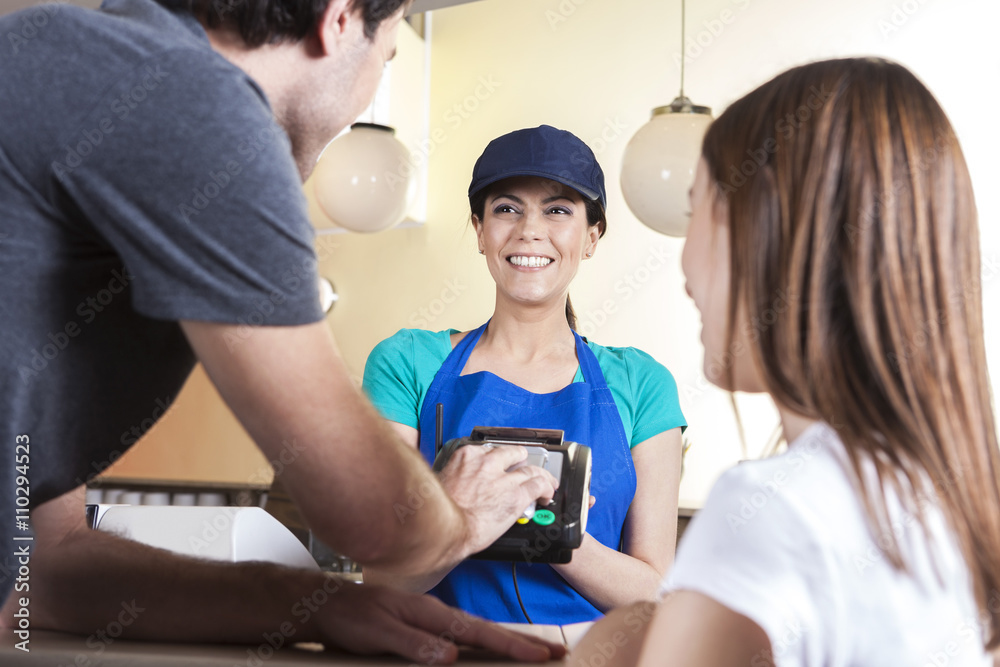 Obraz premium Man Making NFC Payment While Standing With Daughter And Waitress