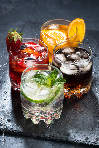 assortment of iced fruit drinks on a dark background, vertical