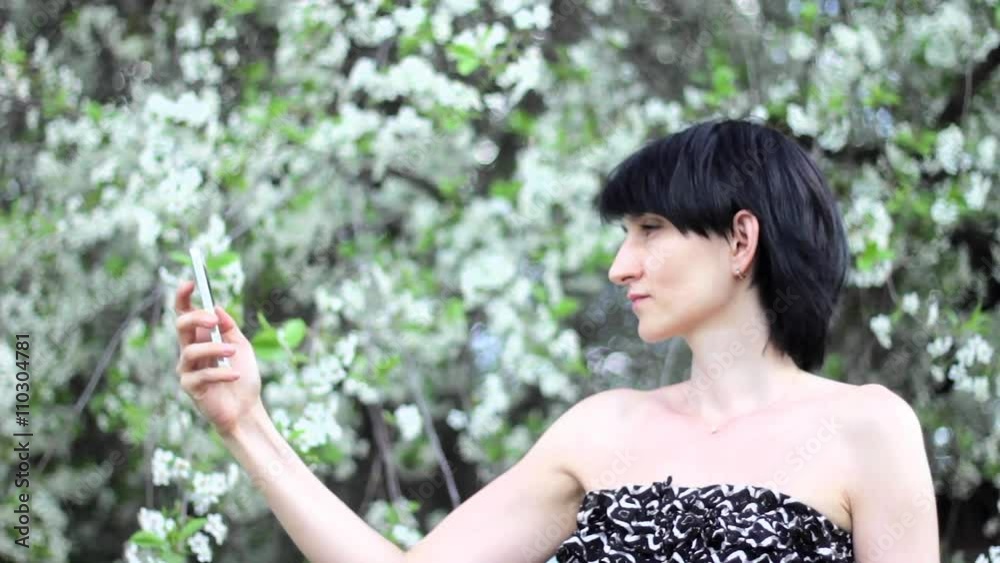 Pretty girl taking a selfie on flowering tree background Pretty girl taking a selfie on flowering tree background