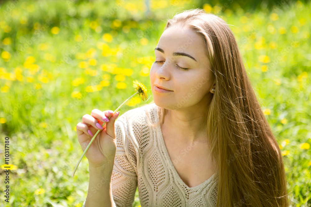 the portrait of the beautiful young woman with long hair with a flower sits on a grass in park
the portrait of the beautiful young woman with long hair with a flower sits on a grass in park