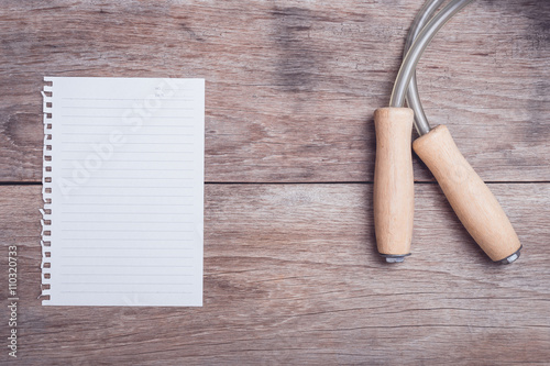 Skipping rope and lined paper on wooden table top view