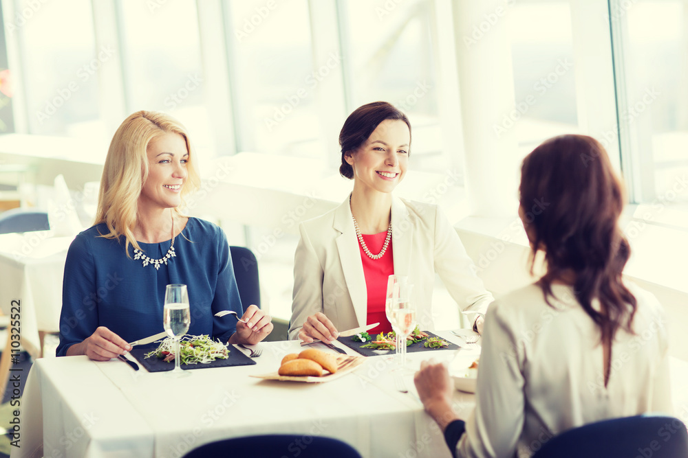 happy women eating and talking at restaurant happy women eating and talking at restaurant