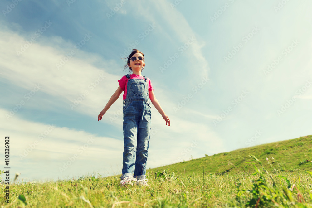 happy little girl over green field and blue sky